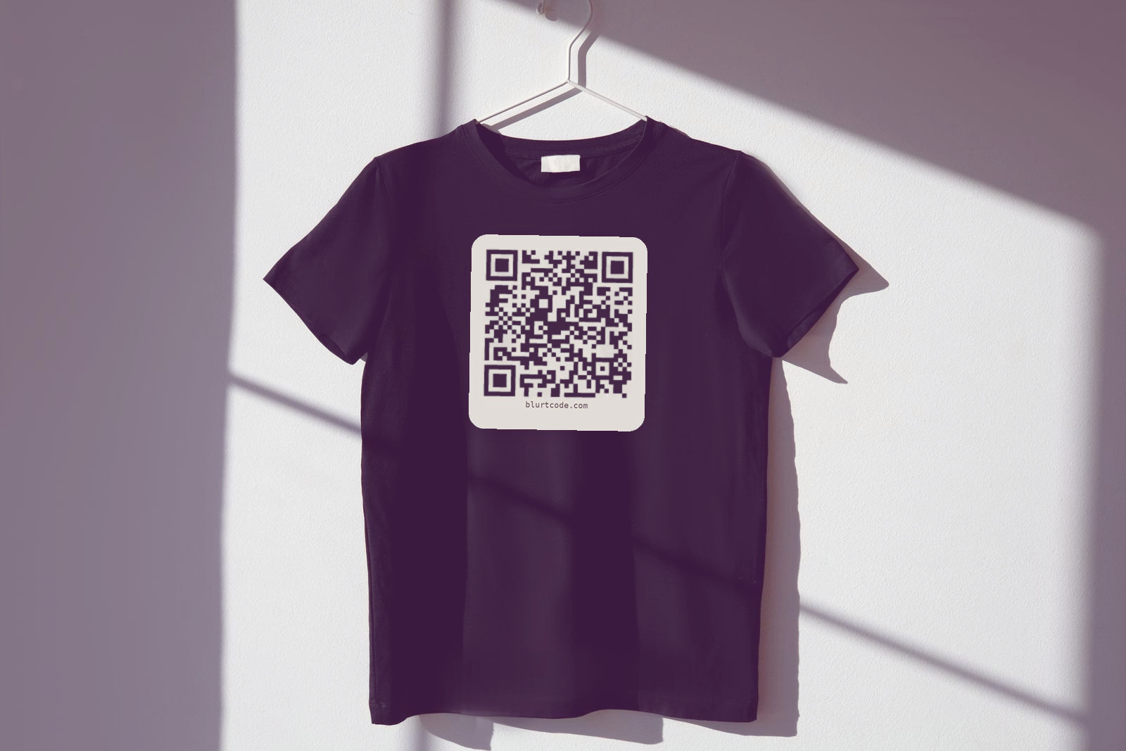 Deep plum t-shirt on a hanger with a cream Blurtcode QR badge on the chest